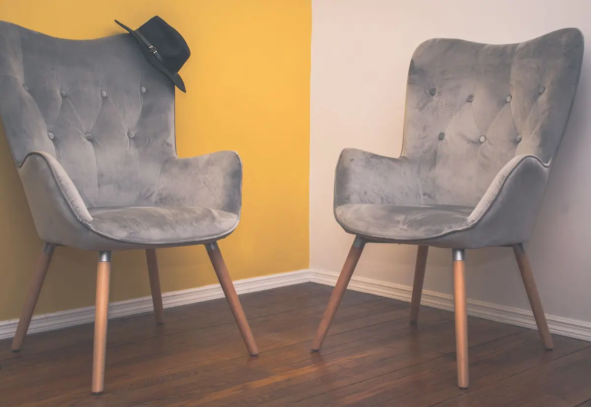 Two upholstered chairs set against a single yellow accent wall in an otherwise pale room