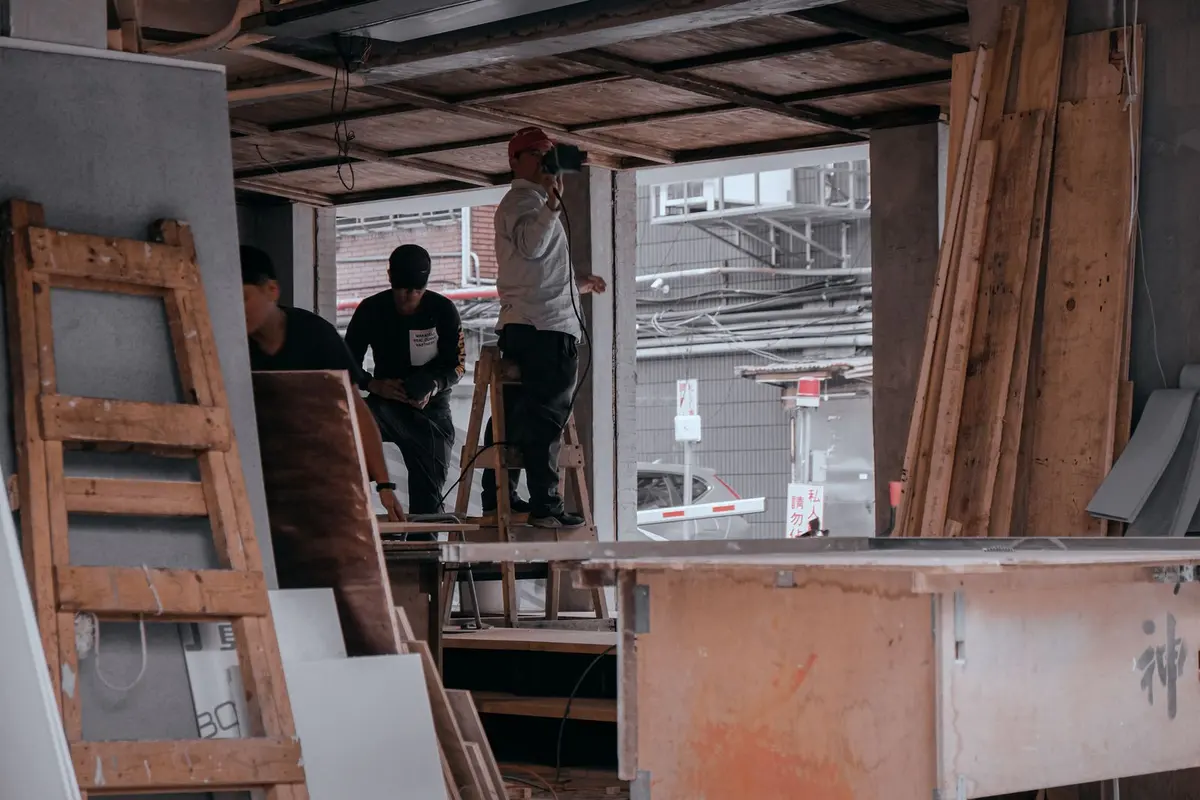 Two workers, one up a ladder, inside a commercial unit being fitted out