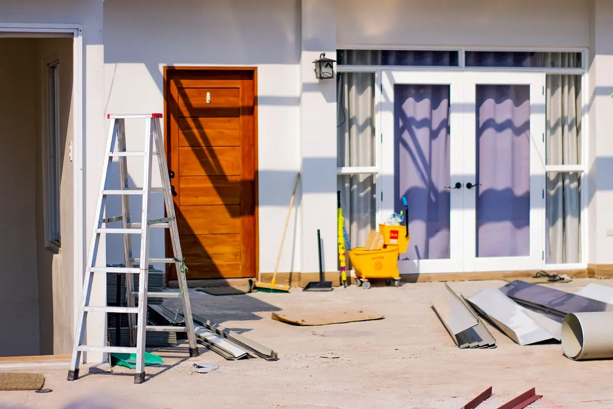 A house entry part-way through a job, with a wooden door off its hinges and the glazed doors masked off behind a stepladder