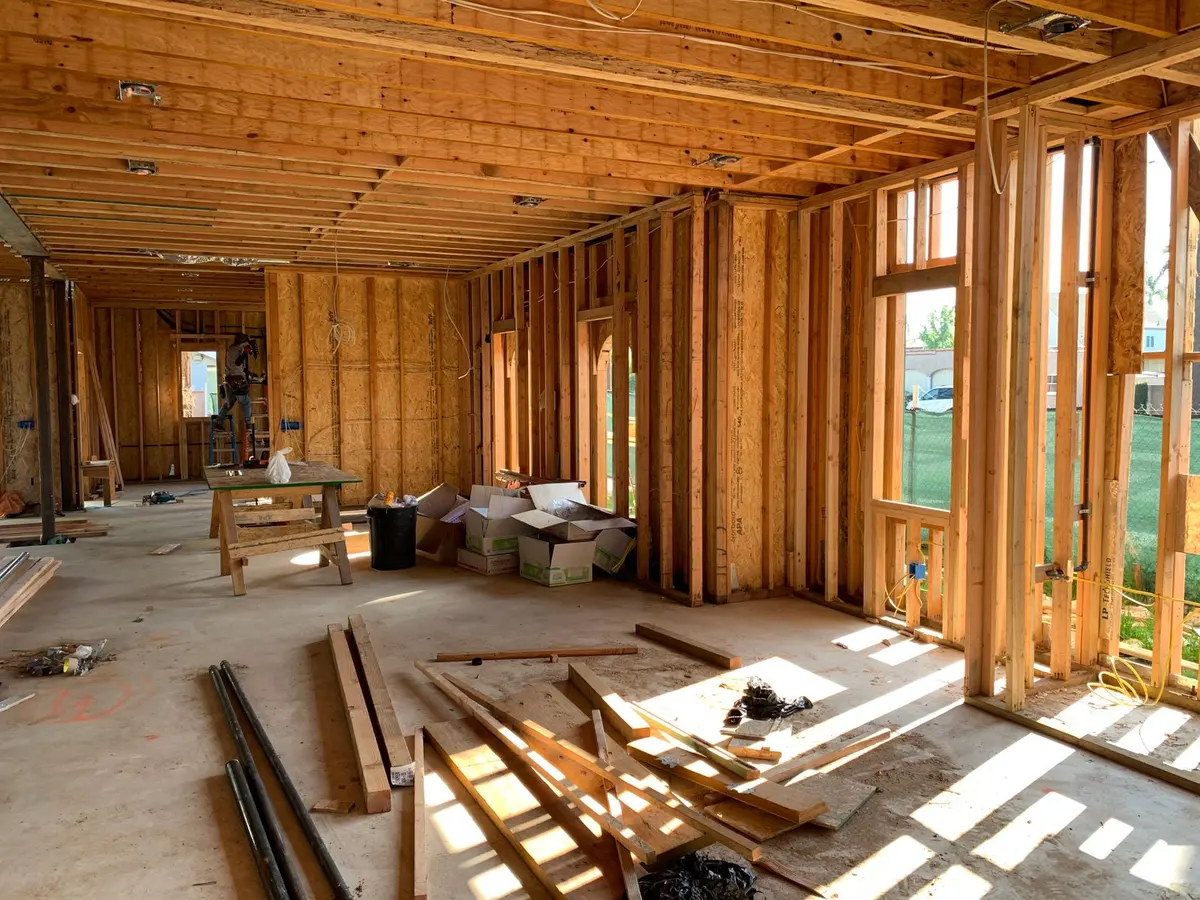 The inside of a house under construction, with wall framing still open to daylight
