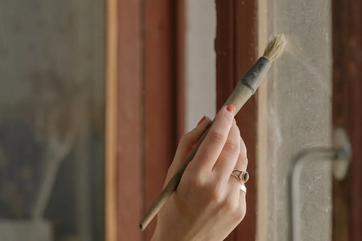 A hand cutting in a clean painted edge along a window frame with a brush
